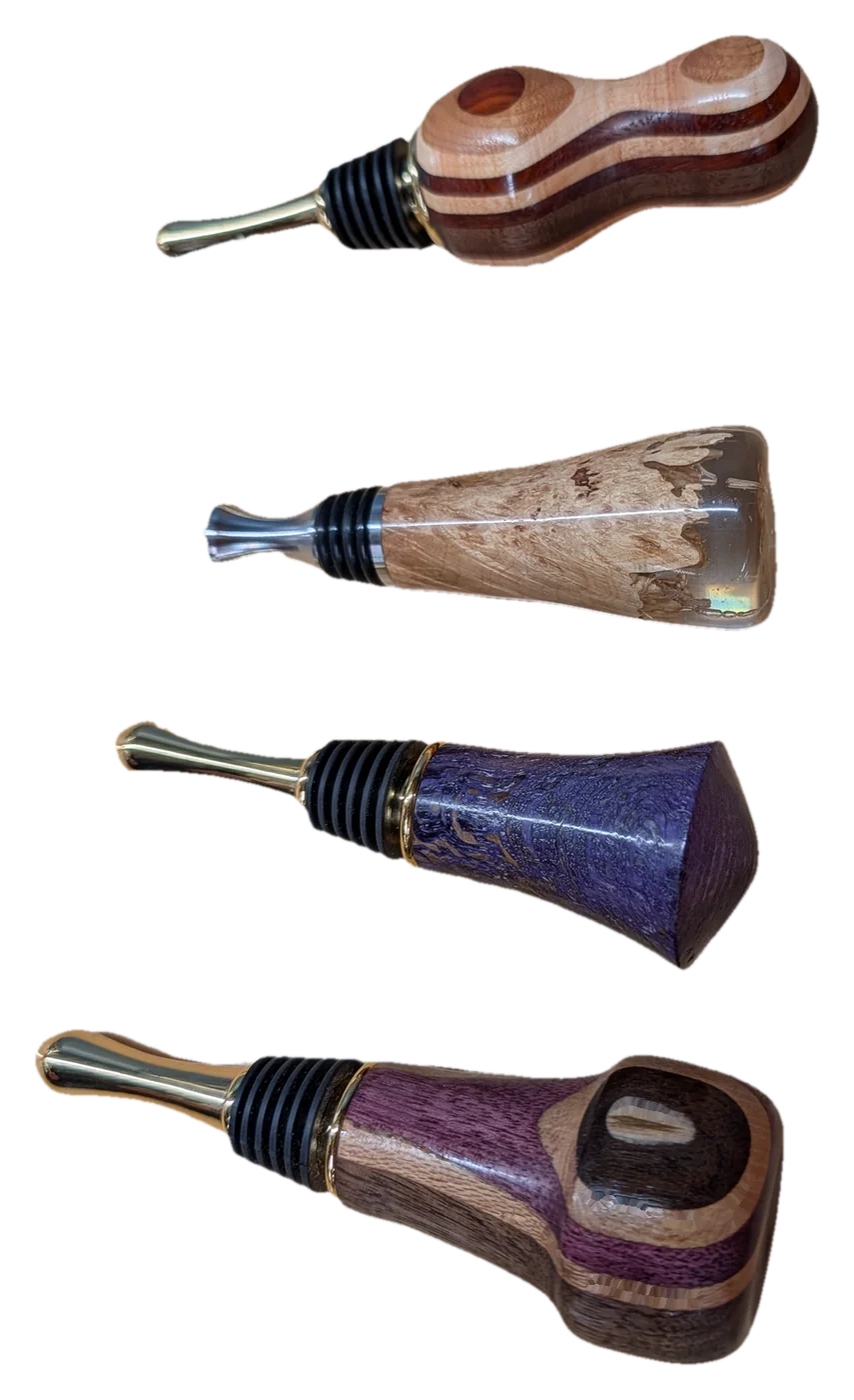 Four turned bottle stoppers in segmented and burl wood, one cast in clear resin